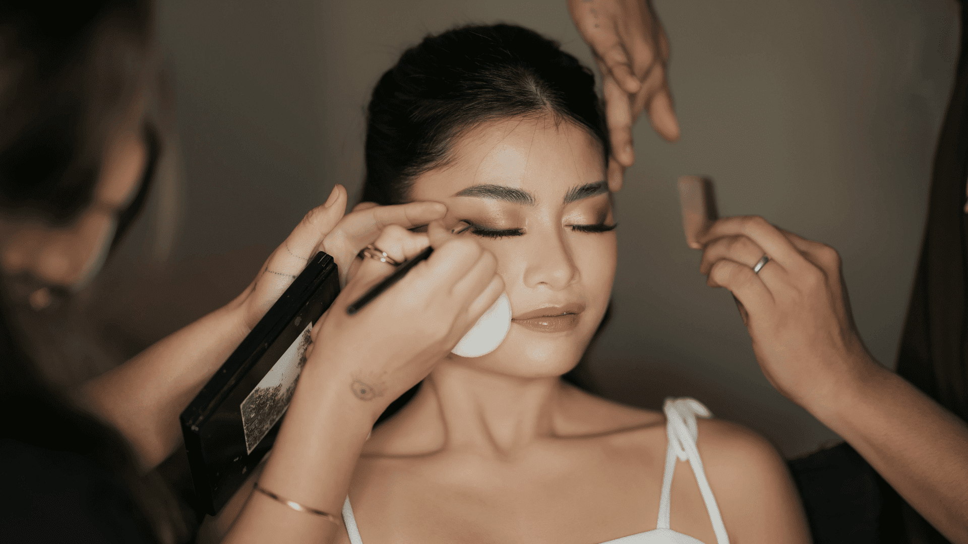 Woman getting professional makeup applied by artists.