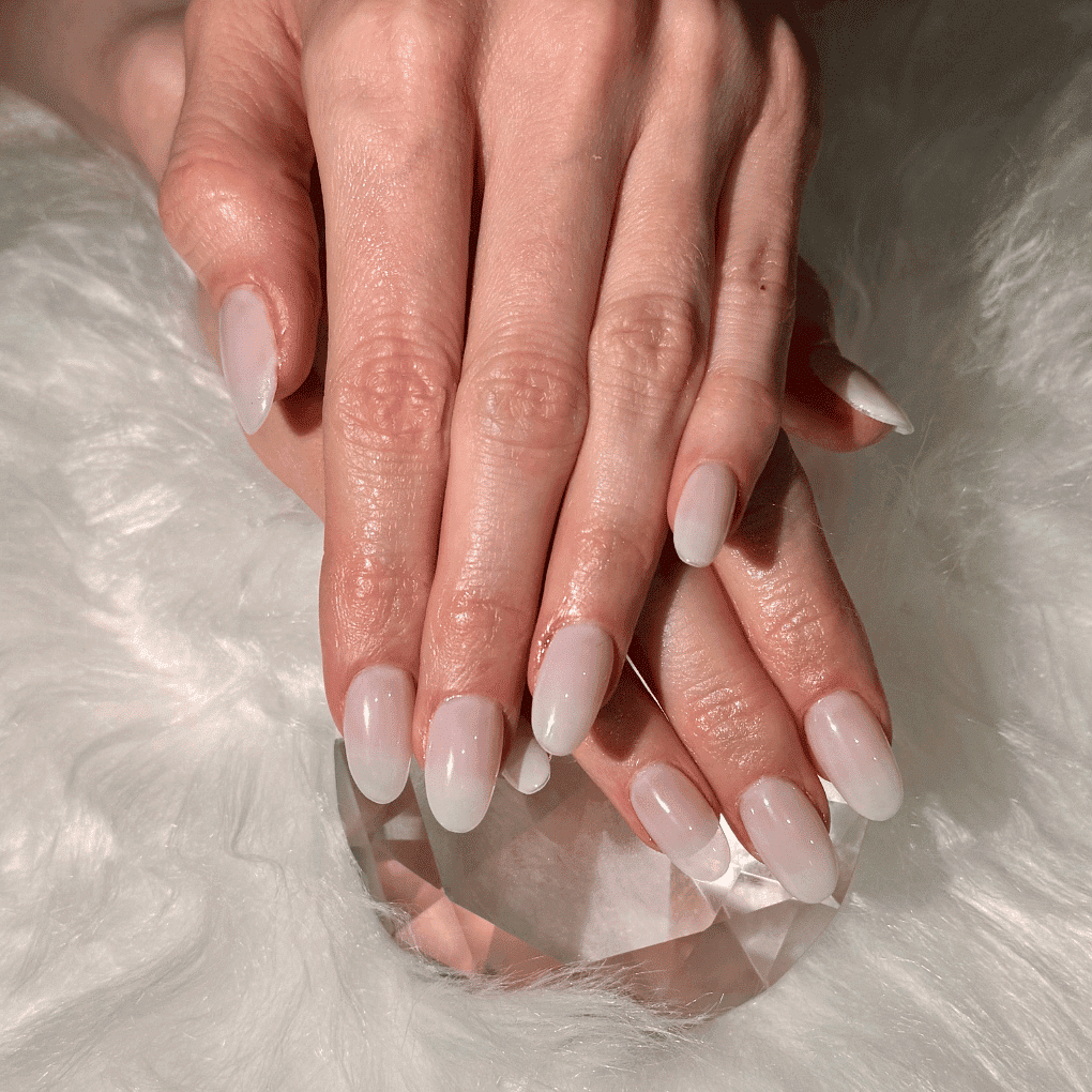 Manicured hands with glossy white nails on a soft, fuzzy surface.