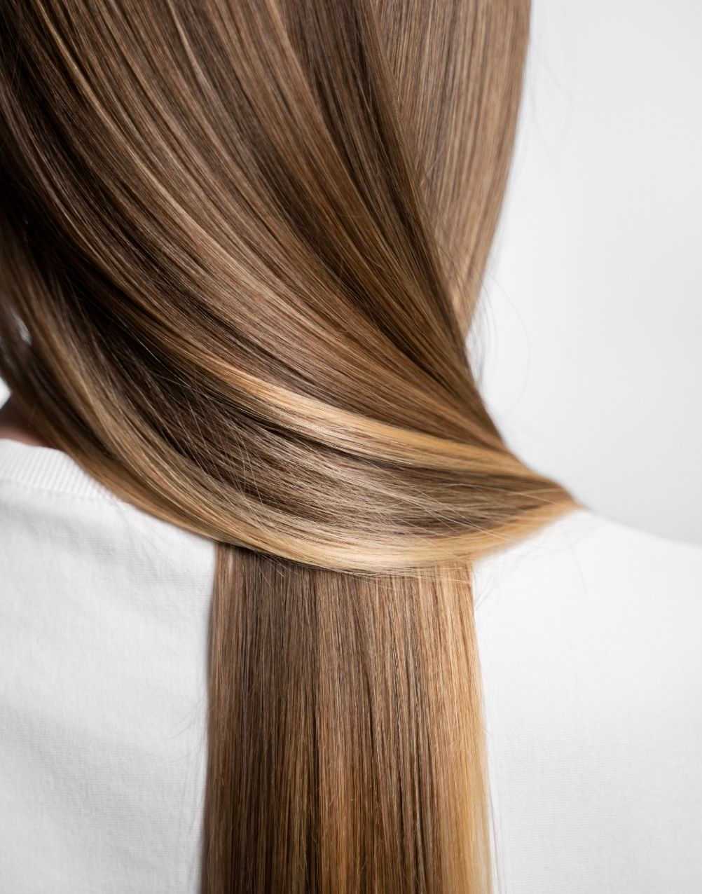 Smooth, shiny light brown hair with subtle highlights against a white background.