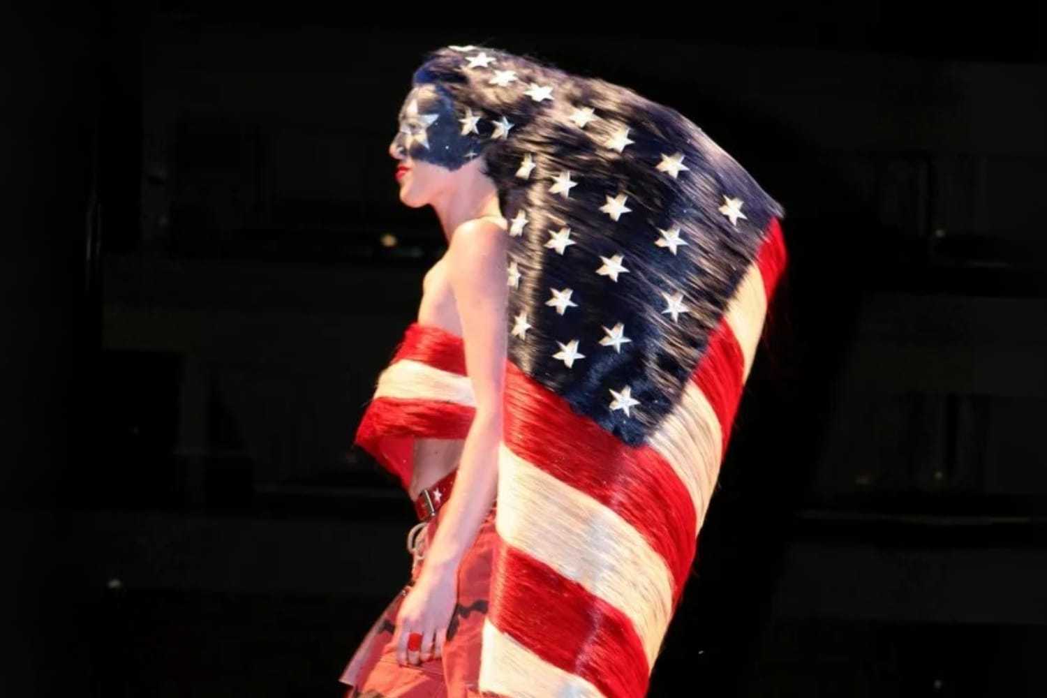 Woman draped in the American flag on stage, face painted with stars and stripes.
