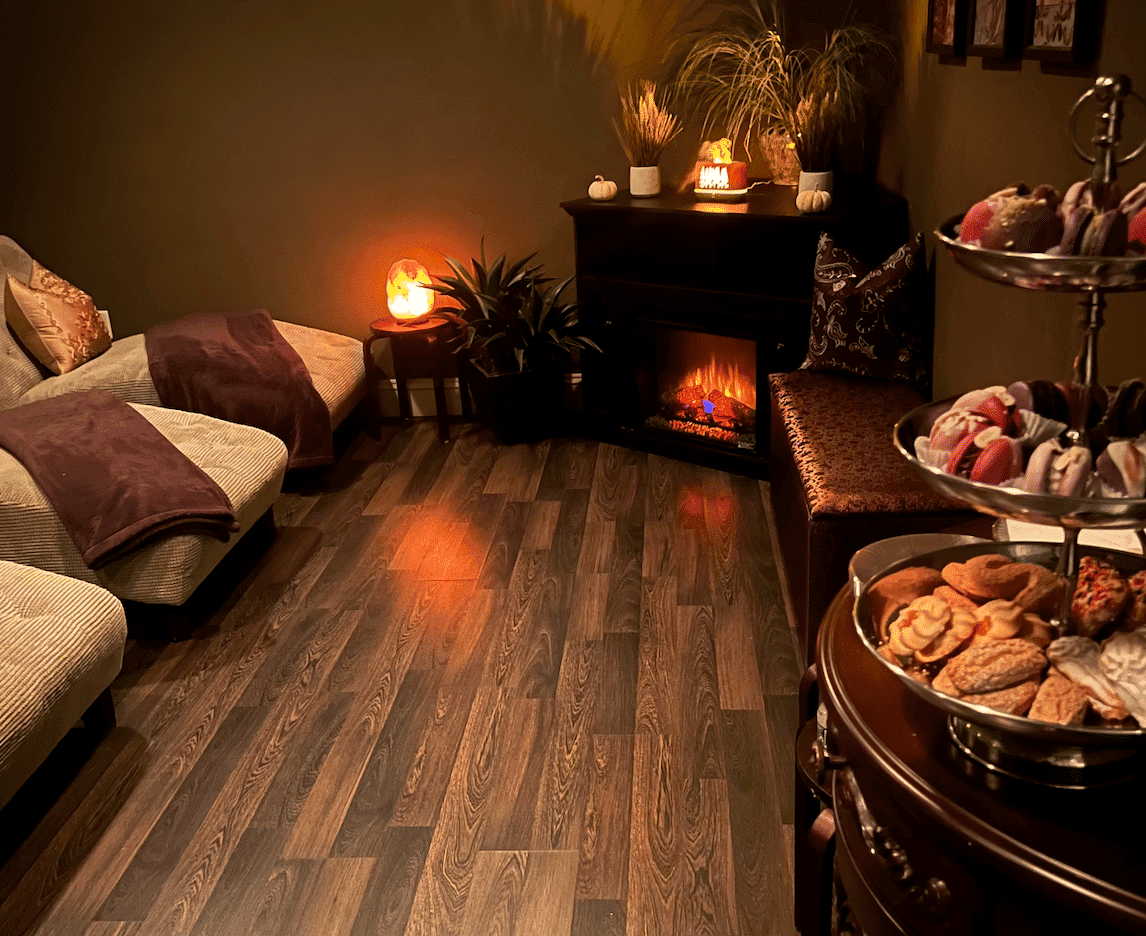 Cozy room with a fireplace, warm lighting, and a tray of cookies and pastries on a table.