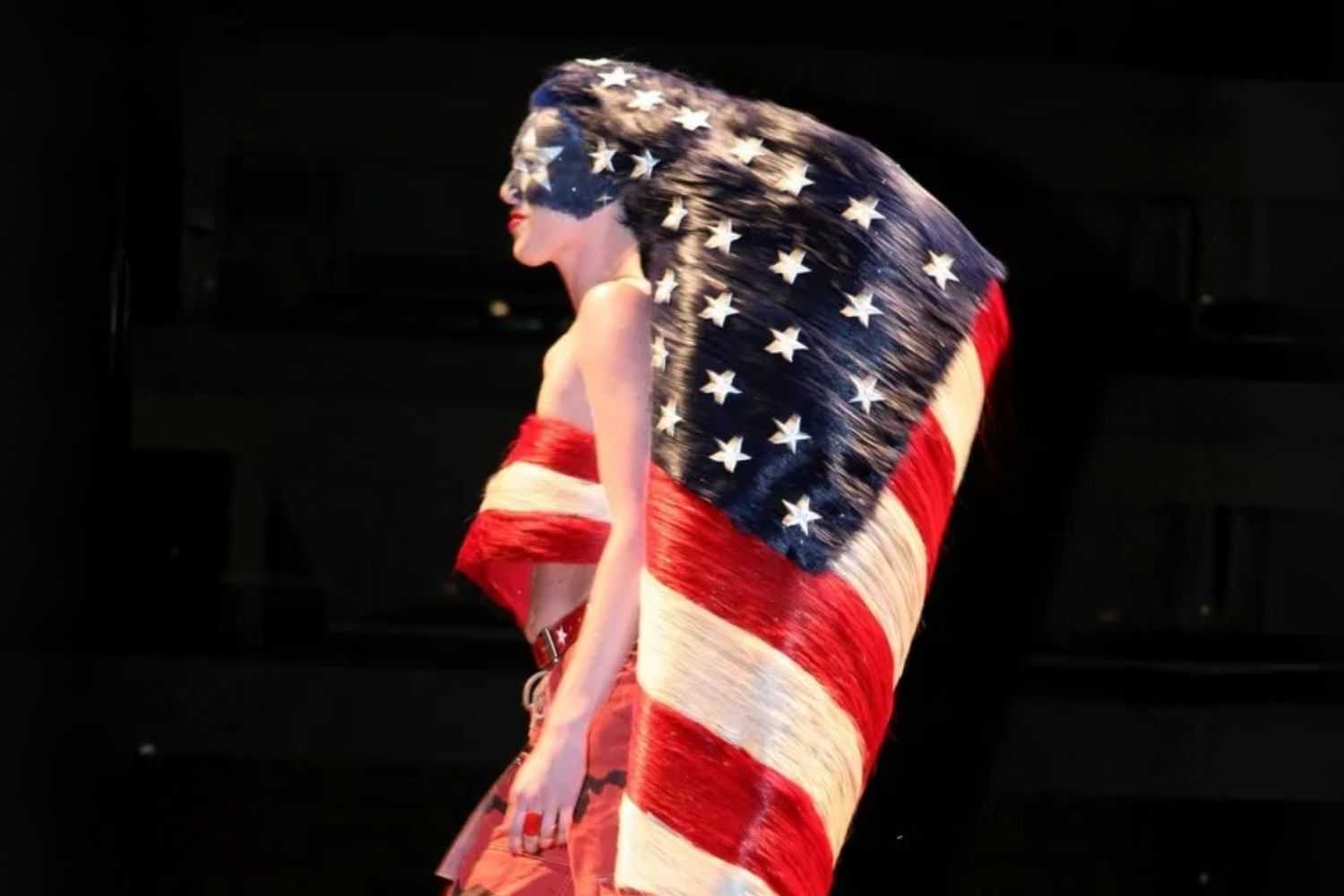 Woman draped in the American flag on stage, face painted with stars and stripes.