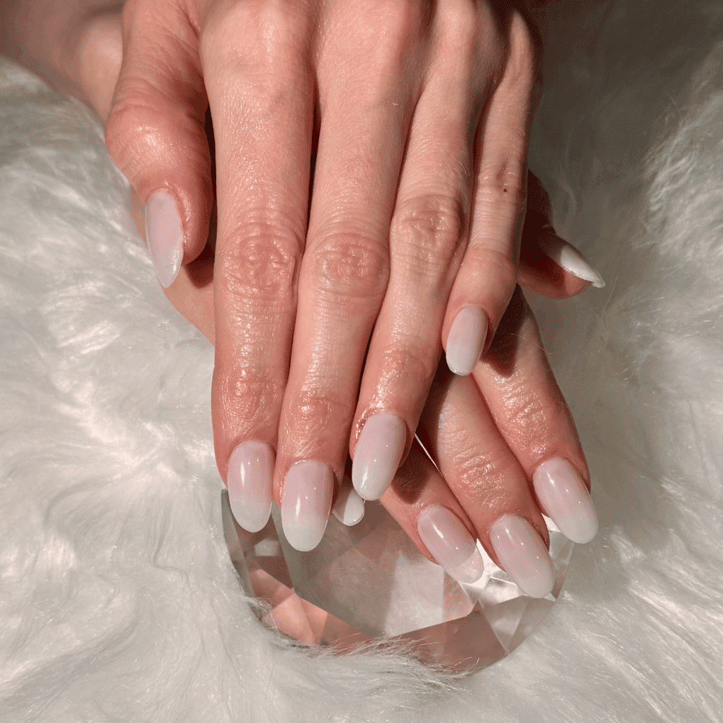 Manicured hands with glossy white nails on a soft, fuzzy surface.